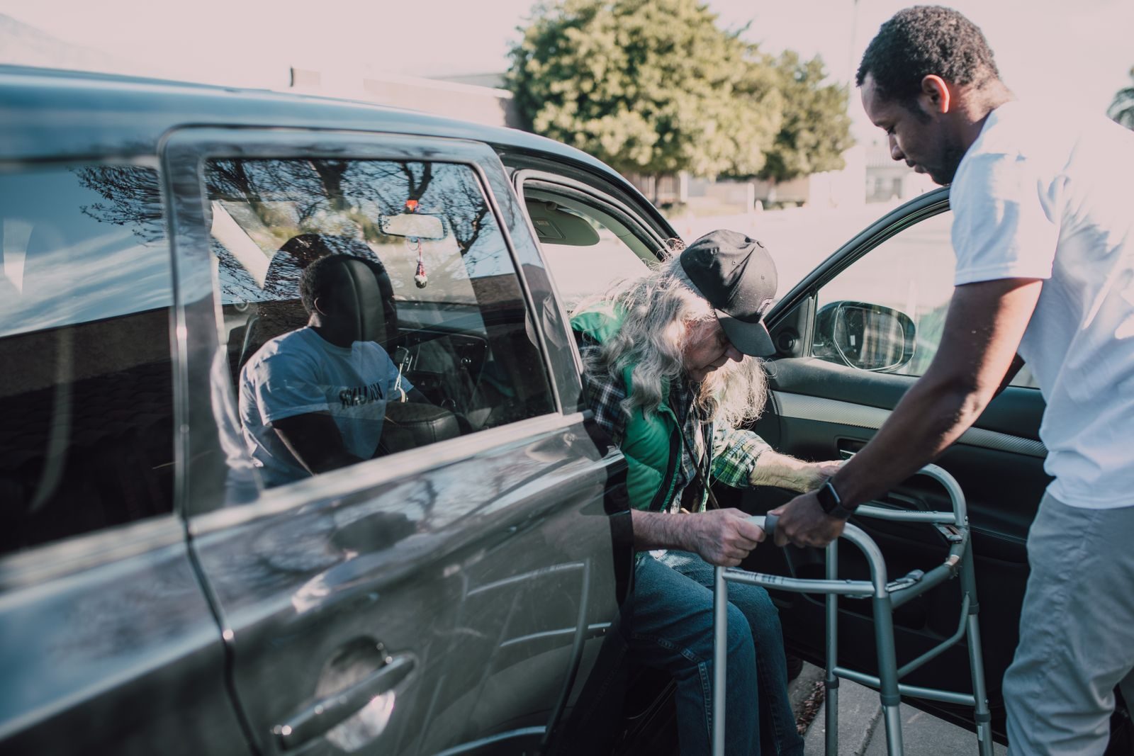 A caregiver helping a passenger into a vehicle